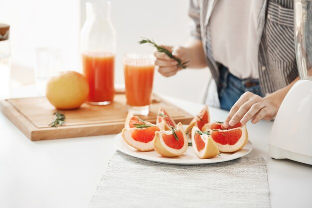 Ciérrese para arriba de la placa de decoración de la muchacha con el pomelo y el romero rebanados. Concepto de nutrición fitness. Copia espacio