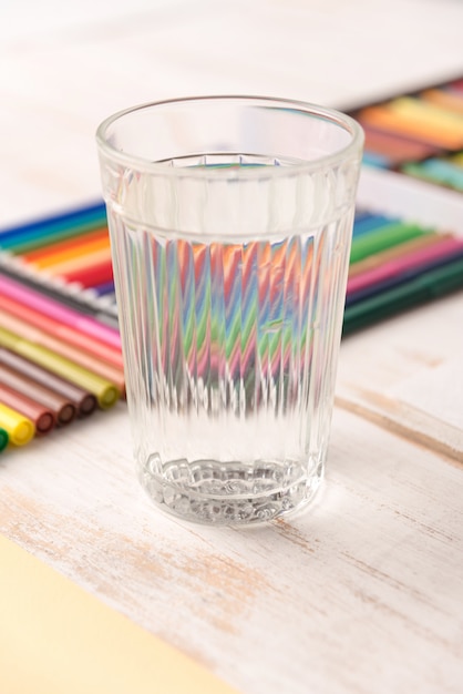 Foto gratuita ciérrese para arriba del vidrio con el agua que se coloca cerca de marcadores coloridos