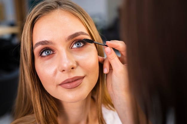 Ciérrese encima del artista de maquillaje que aplica el rimel en mujer