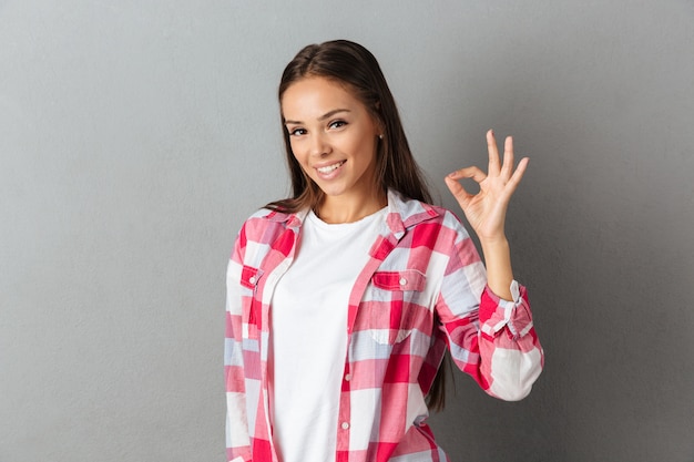 Foto gratuita ciérrese encima de la foto de la mujer morena joven alegre que muestra gesto aceptable