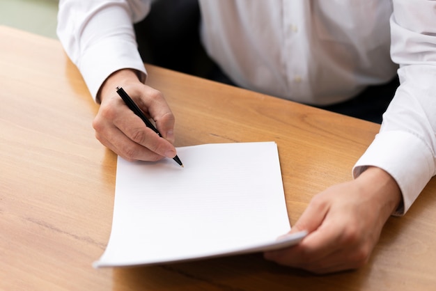 Ciérrese encima del hombre de negocios usando la pluma