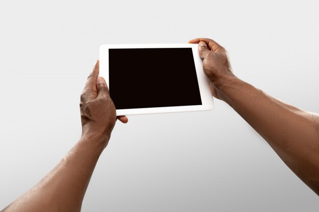 Ciérrese encima de las manos masculinas que sostienen la tableta con la pantalla en blanco durante la observación en línea de partidos deportivos populares y campeonatos en todo el mundo.