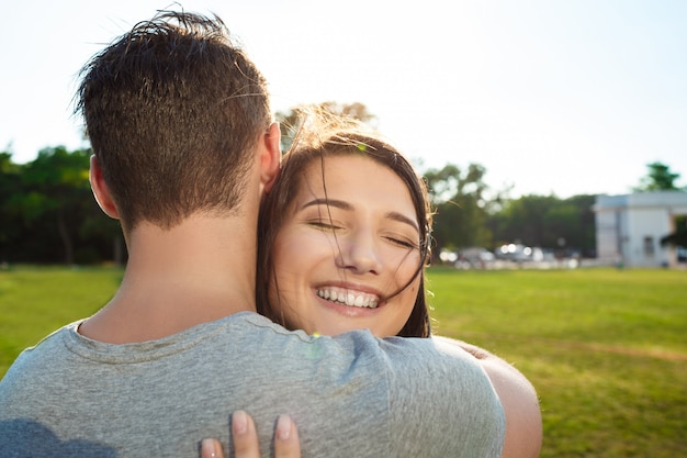 Ciérrese encima de la pareja hermosa joven que abraza en parque.