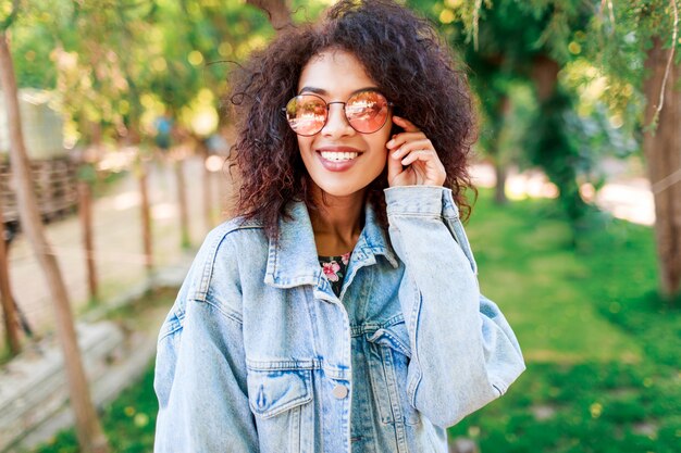 Ciérrese encima del retrato emocional de la señora bonita alegre que juega con sus pelos rizados asombrosos.