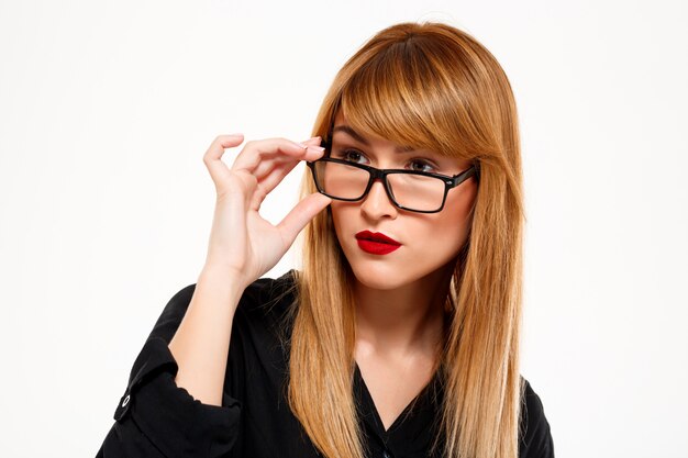 Ciérrese encima del retrato de la empresaria acertada que mira lejos sobre la pared blanca