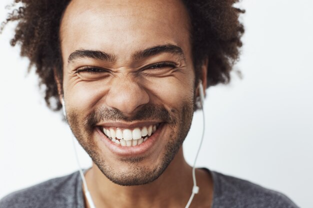 Ciérrese encima del retrato del hombre africano feliz joven que sonríe escuchando la risa optimista de la música que fluye. Concepto de juventud.