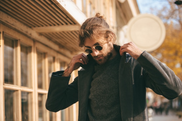 Ciérrese encima del retrato de un hombre barbudo elegante que lleva las gafas de sol