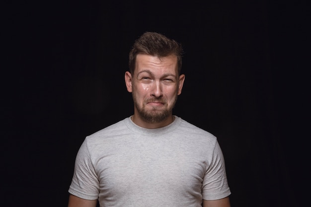 Foto gratuita ciérrese encima del retrato del hombre joven aislado en el espacio negro. photoshot de emociones reales del modelo masculino. llorando, triste, triste y sin esperanza