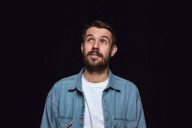 Ciérrese encima del retrato del hombre joven aislado. Soñando y sonriendo, esperanzado y feliz. Expresión facial, concepto de emociones humanas.