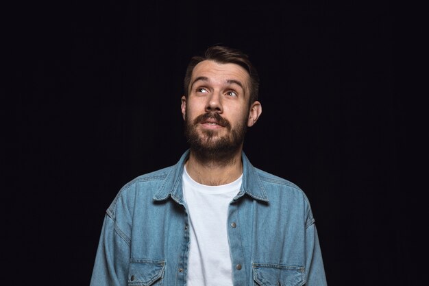 Ciérrese encima del retrato del hombre joven aislado. Soñando y sonriendo, esperanzado y feliz. Expresión facial, concepto de emociones humanas.