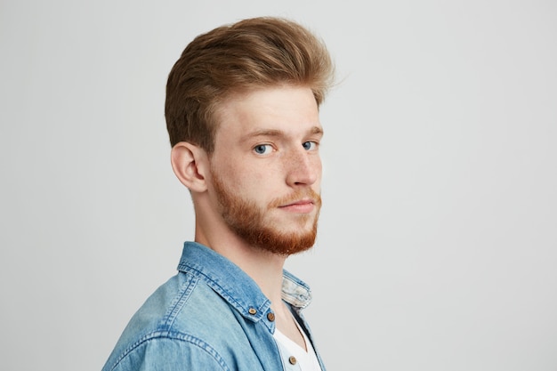 Foto gratuita ciérrese encima del retrato del hombre joven hermoso del inconformista con la camisa de la mezclilla de la barba que lleva.