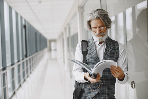 Ciérrese encima del retrato del hombre pasado de moda sonriente. Hombre elegante en la oficina. Senior con documentos.