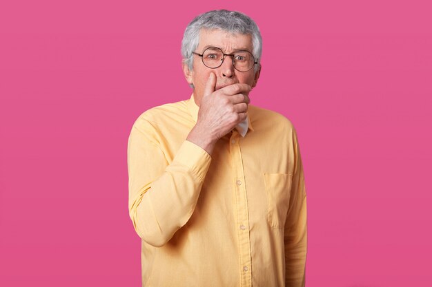 Ciérrese encima del retrato del hombre con los vidrios redondeados negros, la camisa amarilla vestida y la corbata de lazo. Eldery senior con los ojos bien abiertos, ha sorprendido la expresión facial, temeroso de algo, con la boca en boca.