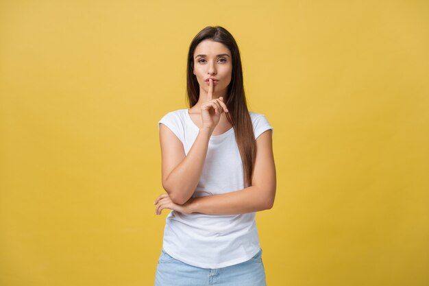 Ciérrese encima del retrato de inseguro incierto atractivo encantador lindo con el emprendedor elegante del peinado que hace el gesto de silencio aislado en el espacio de la copia del fondo amarillo.