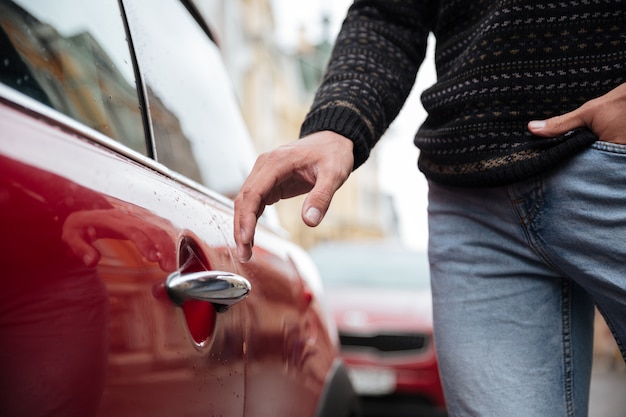 Ciérrese encima del retrato de una mano masculina en la manija del coche al aire libre