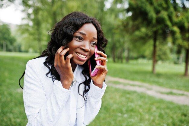 Ciérrese encima del retrato de la muchacha afroamericana negra elegante con el teléfono móvil rosado