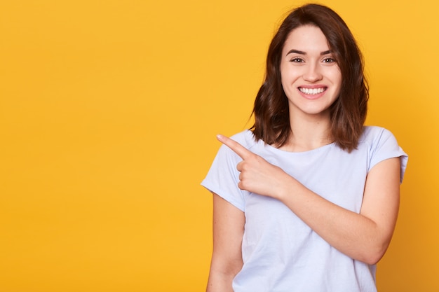 Foto gratuita ciérrese encima del retrato de la muchacha alegre encantadora linda sonriente adorable linda que señala con su dedo índice