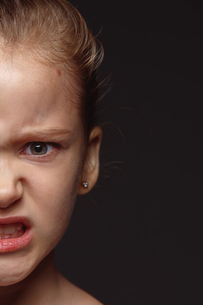 Ciérrese encima del retrato de la muchacha caucásica pequeña y emocional. Photoshot muy detallado de modelo femenino con piel bien cuidada y expresión facial brillante. Concepto de emociones humanas. Enojado, mirando a la cámara.