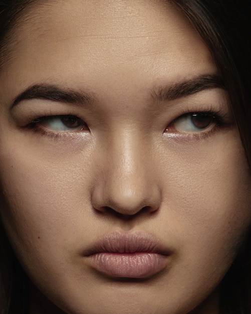 Ciérrese encima del retrato de la mujer china joven y emocional. Photoshot muy detallado de modelo femenino con piel bien cuidada y expresión facial brillante. Concepto de emociones humanas. Grave, mirando de lado.