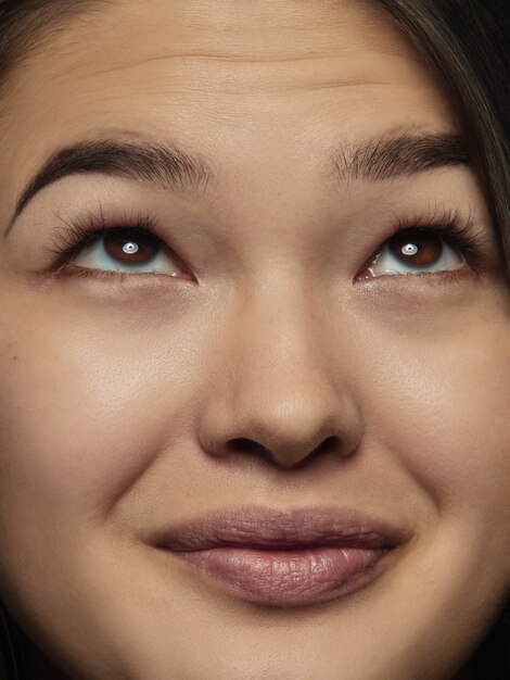 Ciérrese encima del retrato de la mujer china joven y emocional. Photoshot muy detallado de modelo femenino con piel bien cuidada y expresión facial brillante. Concepto de emociones humanas. Mirando hacia arriba, sonriendo.