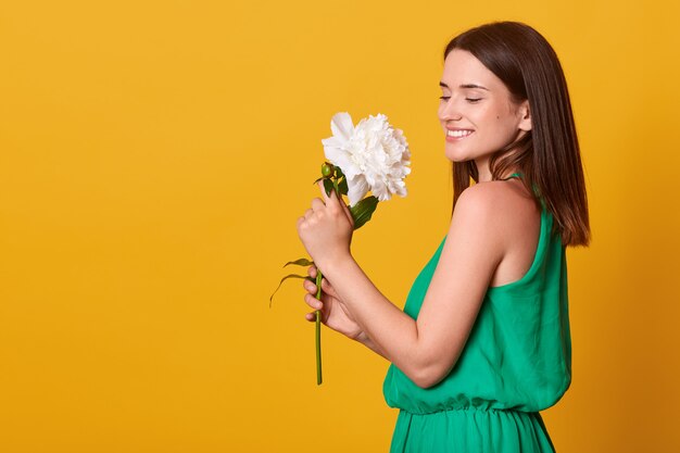 Ciérrese encima del retrato de la mujer joven adorable que se coloca aislada sobre rosa