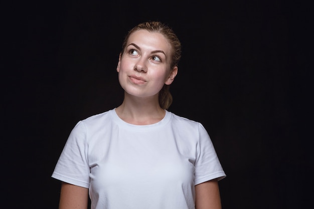 Ciérrese encima del retrato de la mujer joven aislada en el fondo negro del estudio.