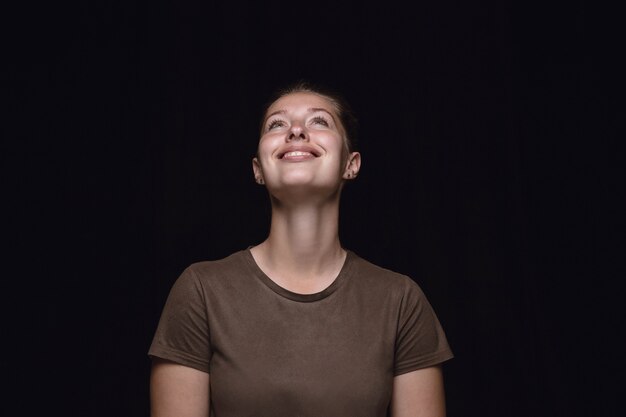 Ciérrese encima del retrato de la mujer joven aislada en el fondo negro del estudio.