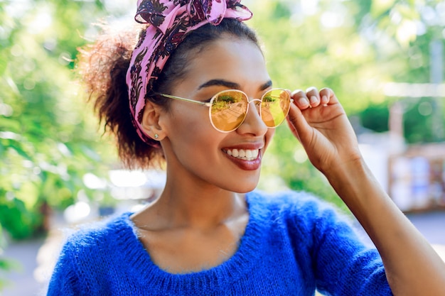 Ciérrese encima del retrato de la mujer negra sonriente en vidrios de moda.