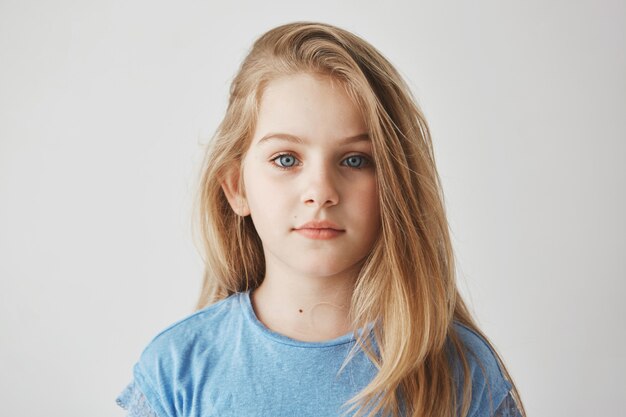 Ciérrese encima del retrato de la niña hermosa con el pelo largo claro y los ojos azules grandes con la expresión relajada.