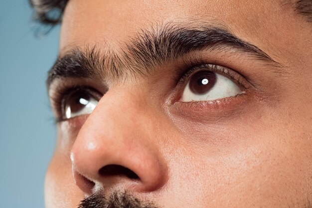 Ciérrese encima del retrato del rostro del joven indio con ojos marrones mirando hacia arriba o al lado. Emociones humanas, expresión facial. Luciendo soñadora o esperanzada.