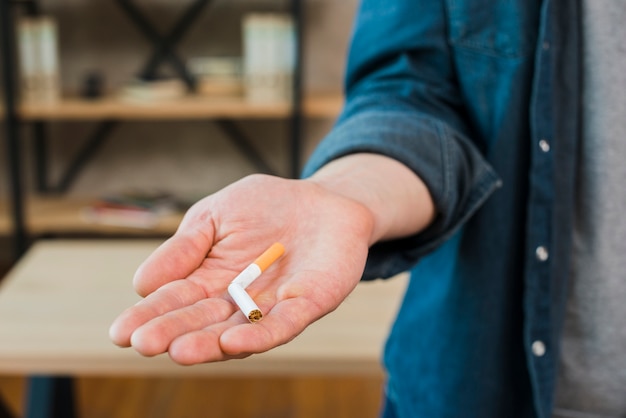 Cigarrillo roto en la mano del hombre