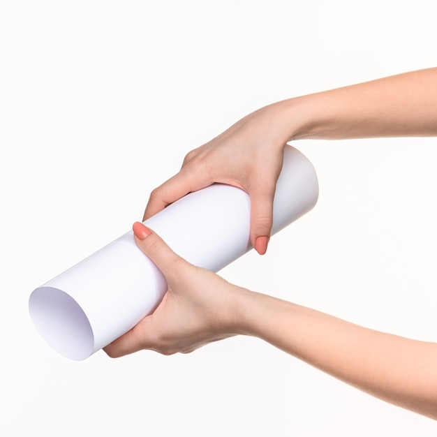 El cilindro blanco de los accesorios en las manos femeninas en blanco