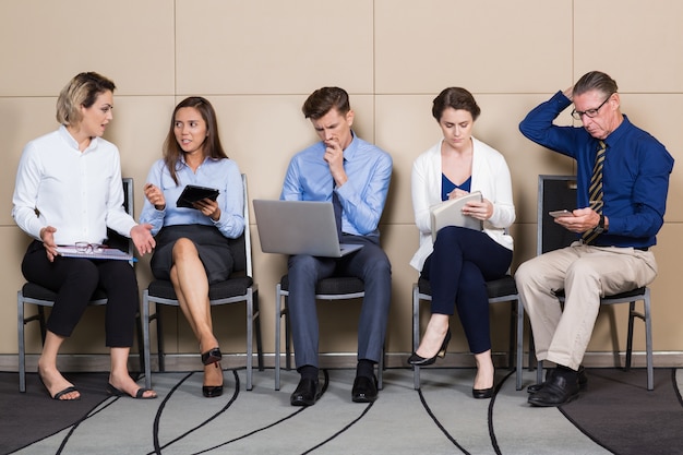 Cinco solicitantes de trabajo en una empresa sentado en la fila