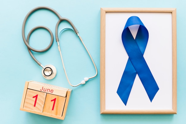 Cinta azul de conciencia de la semana de la salud de Men�s en marco blanco de madera y estetoscopio