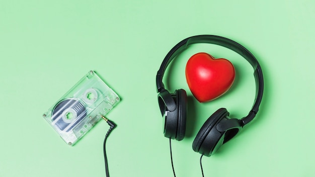 Cinta de cassette transparente conectada con auriculares alrededor del corazón rojo