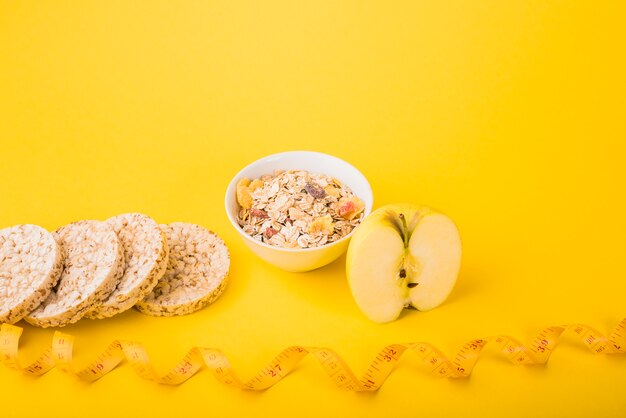 Cinta métrica cerca de fruta, pan crujiente y tazón de muesli