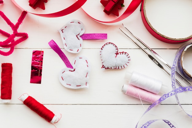 Cinta roja y morada; carretes Aguja de ganchillo y forma de corazón en tablón blanco