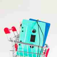Foto gratuita cintas de cassette de color turquesa y azul en carrito de la compra contra el telón de fondo blanco