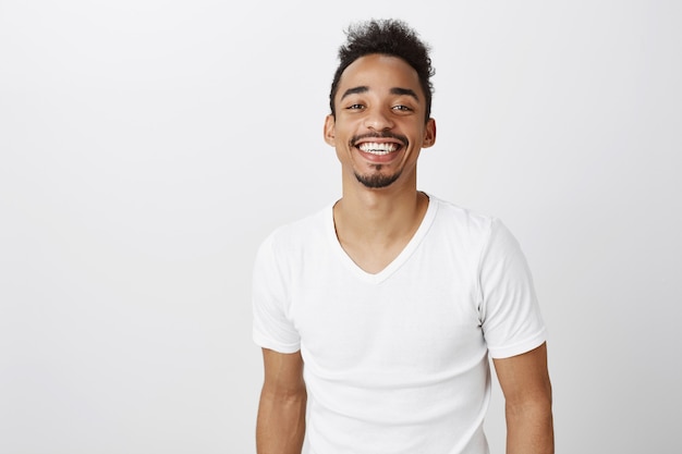 Cintura para arriba del apuesto hombre afroamericano sonriente en camiseta casual blanca que parece feliz