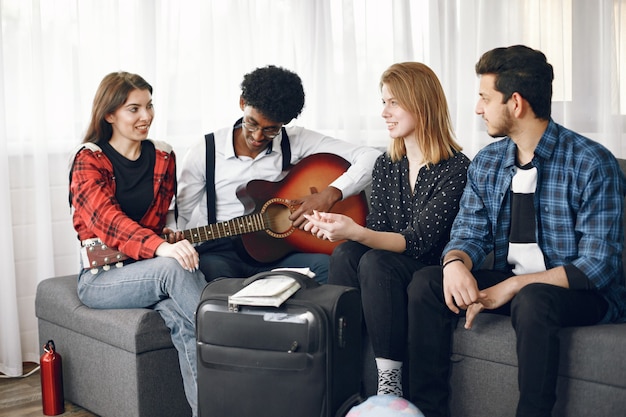 Círculo de amigos diversos reunidos en casa. Un chico cantando mientras toca la guitarra.