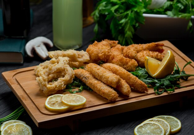 Círculos de cebolla y palitos de pollo asados servidos con rodajas de limón.