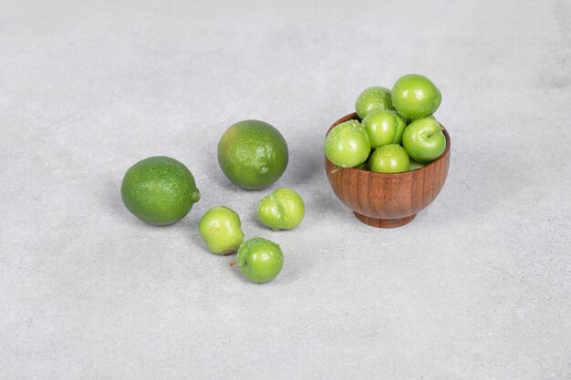 Ciruelas cerezas y frutas de lima en la mesa de la cocina