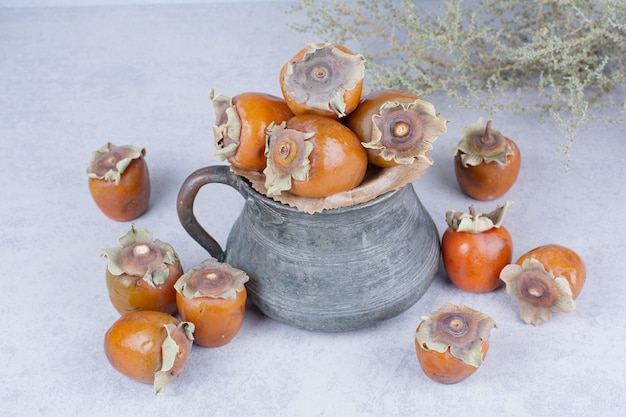 Ciruelas datileras amarillas en una olla metálica sobre gris.