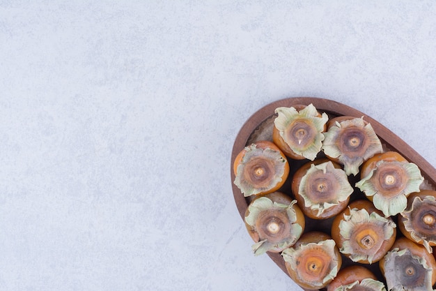 Foto gratuita ciruelas de fecha en una bandeja de madera sobre fondo gris