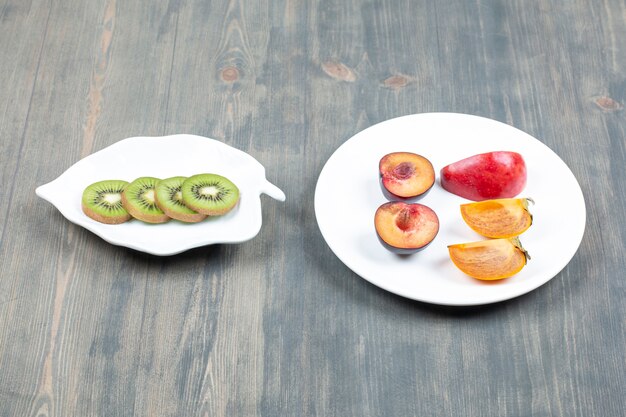 Ciruelas frescas en rodajas con jugoso kiwi en una mesa de madera