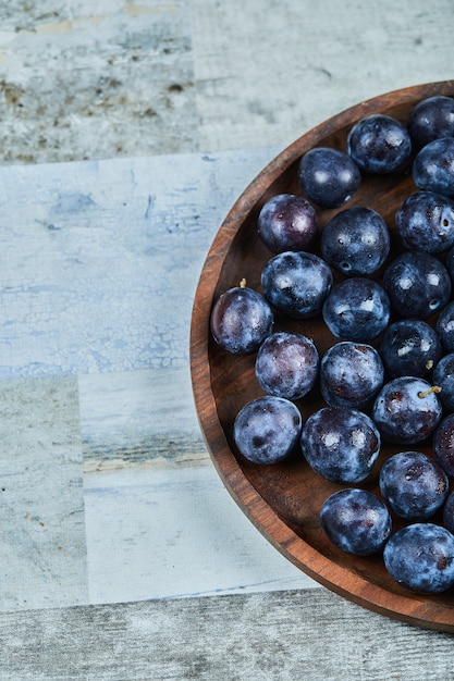 Foto gratuita ciruelas de jardín en un plato en azul.