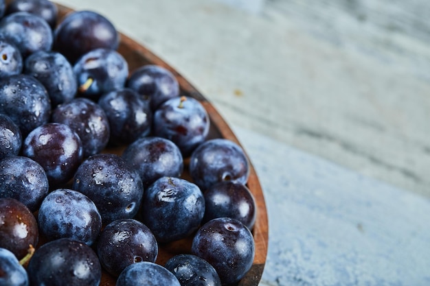 Ciruelas de jardín en un plato sobre un fondo azul. Foto de alta calidad