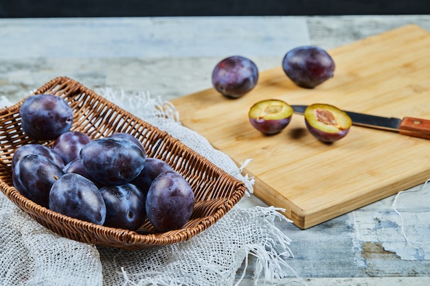 Ciruelas maduras enteras y medio cortadas sobre tabla de madera.