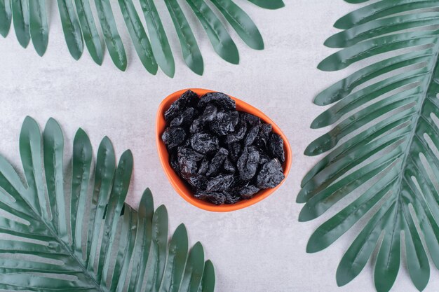 Ciruelas negras secas en una taza de comida sobre una superficie de hormigón