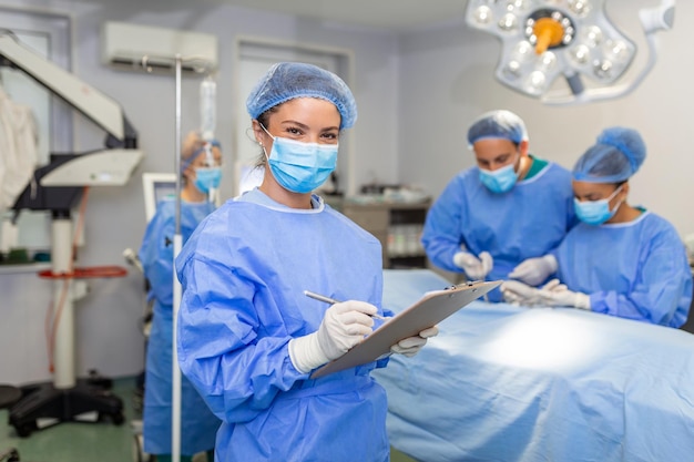 Cirujano escribiendo en el portapapeles en el anestesiólogo de la sala de operaciones escribiendo las actualizaciones